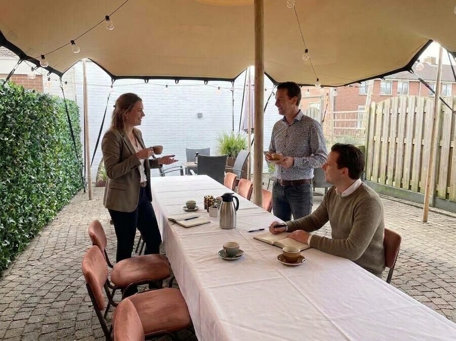 Collega's nemen een korte pauze met koffie in de patio tijdens een heidag bij De Weijenborg